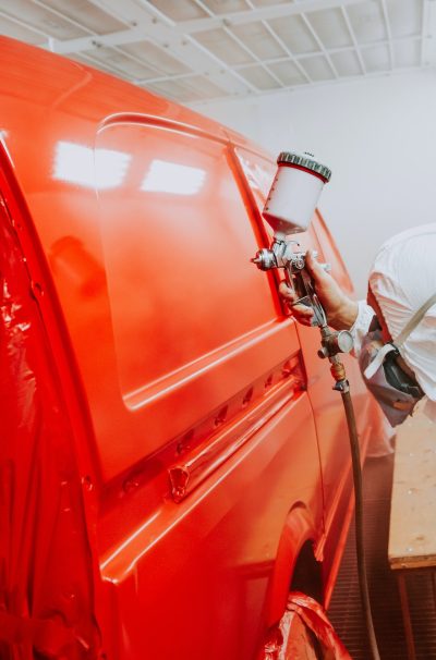 engineer painting and working on a red bodywork of a car and wearing protective gear