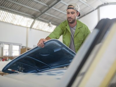 Man fitting car part in bodywork repair shop